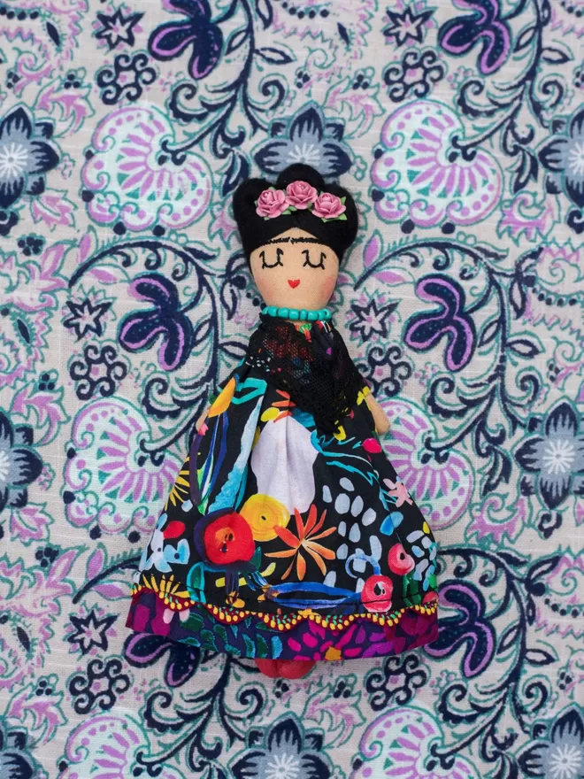 Jennifer Jackson Frida Khalo doll seen on a patterned fabric.