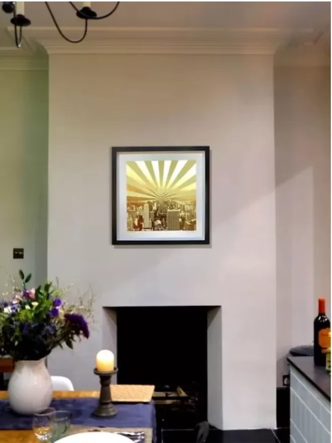 Living room with vase of flowers on a table and gold artwork hanging on the wall above a fireplace 