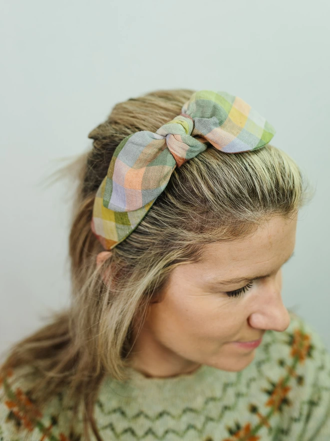 Model in side bow hairband in green check