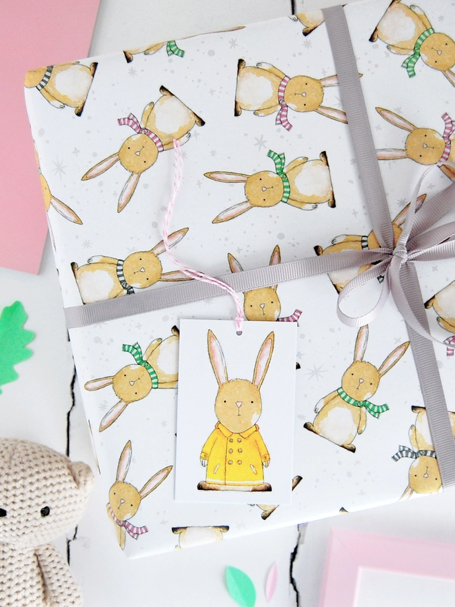 A new baby gift is wrapped is in wrapping paper with a baby rabbit design.