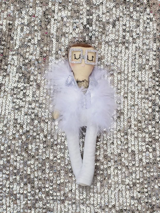 Elton John Jennifer Jackson Doll seen on a sequin fabric.
