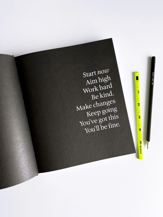HELLO TIME planner open on a black quote page next to a neon ruler and black pencil. 