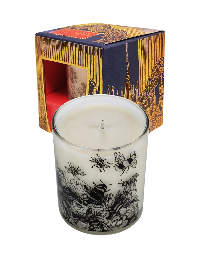bee free oats & honey  charity candle in a reusable decorated glass with black illustrations next to the box