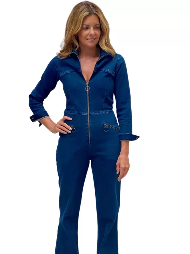 model posing with a hand on her hip wearing the ruby denim jumpsuit with long sleeves