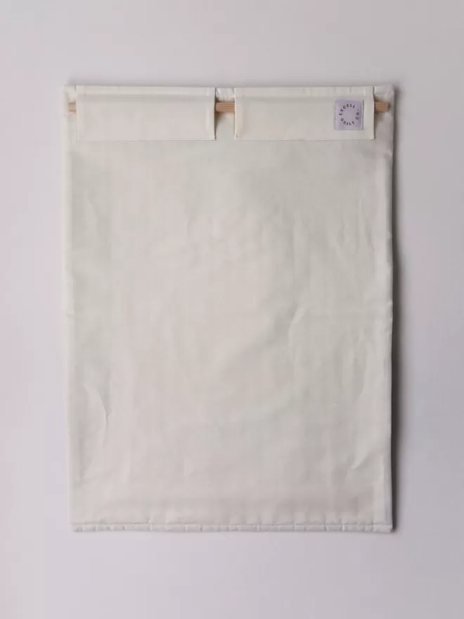 Back Of Crescent Quilt Hanging On White Wall Displaying Hanging Pouch and Wooden Dowel