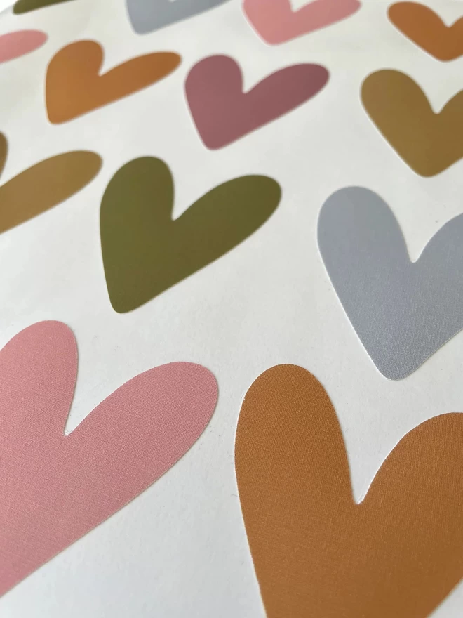 Close up of muted rainbow coloured heart shaped wall stickers