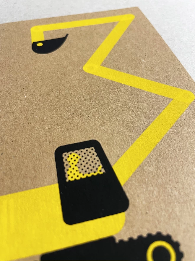 Close up of a brown kraft greetings card with a yellow and black digger. It has been screenprinted in two colours and the arm of the digger makes a number 3.