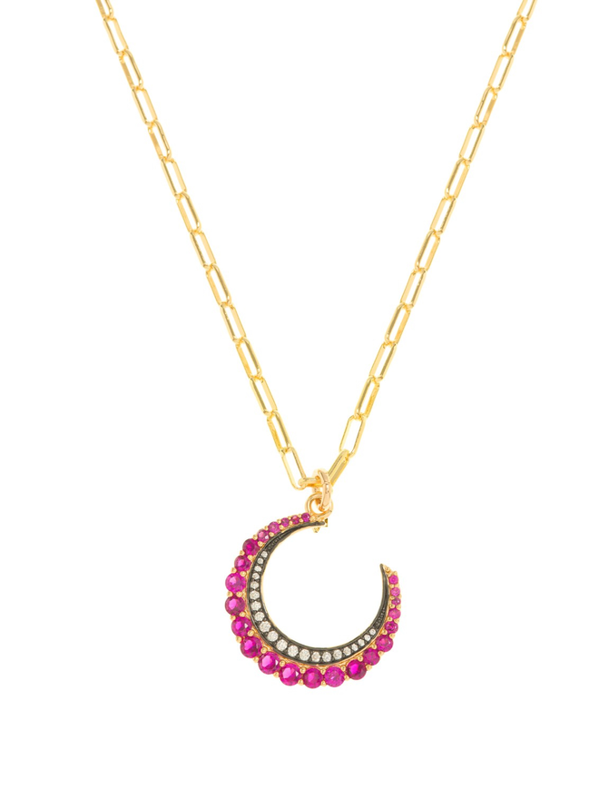 Pink jewelled crescent moon charm hanging from a gold paperclip chain necklace on a white background