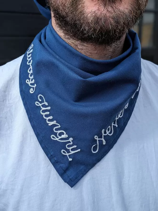 Man wearing a blue Bandana Neckerchief with White Embroidered lettering readiing "Always Hungry, Never Full"