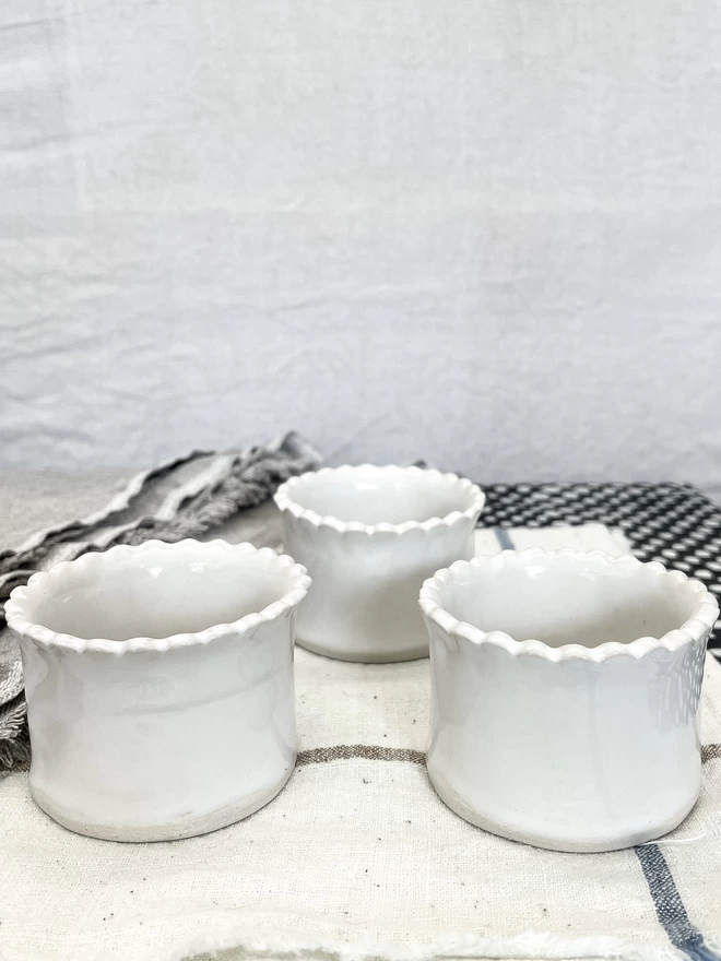 side view of three scalloped edge white egg cups