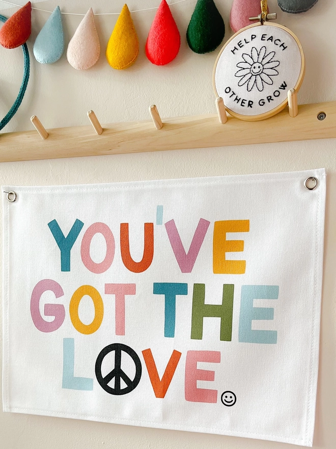 Bright coloured wall hanging saying you’ve got the love hanging on a cream wall