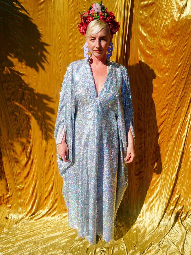 Silver Holographic Sequin V-neck Kaftan Gown standing with her arms down.