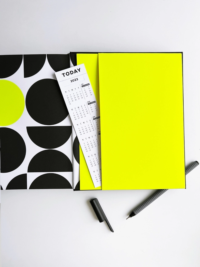 Neon yellow planner pocket in the back of a Haus planner containing a bookmark