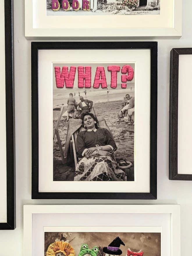  B&W photo print of woman with pink embroidered ‘What?”’ framed on wall 