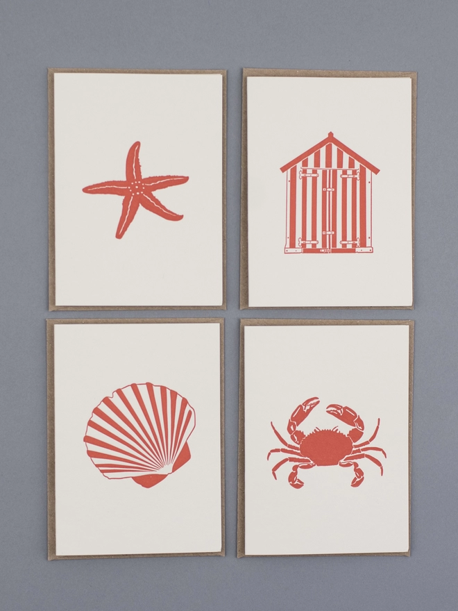 Four of the orange designs included in the beside the sea little note box which are the starfish, crab, beach hut and shell