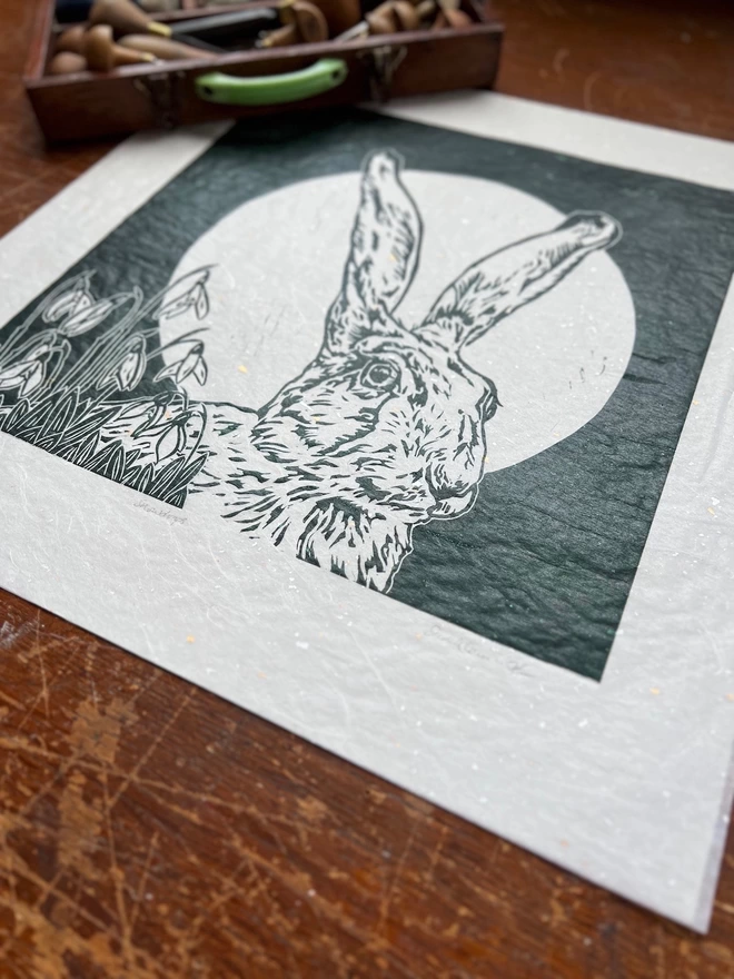 linocut of hare head, full moon and snowdrops in green ink