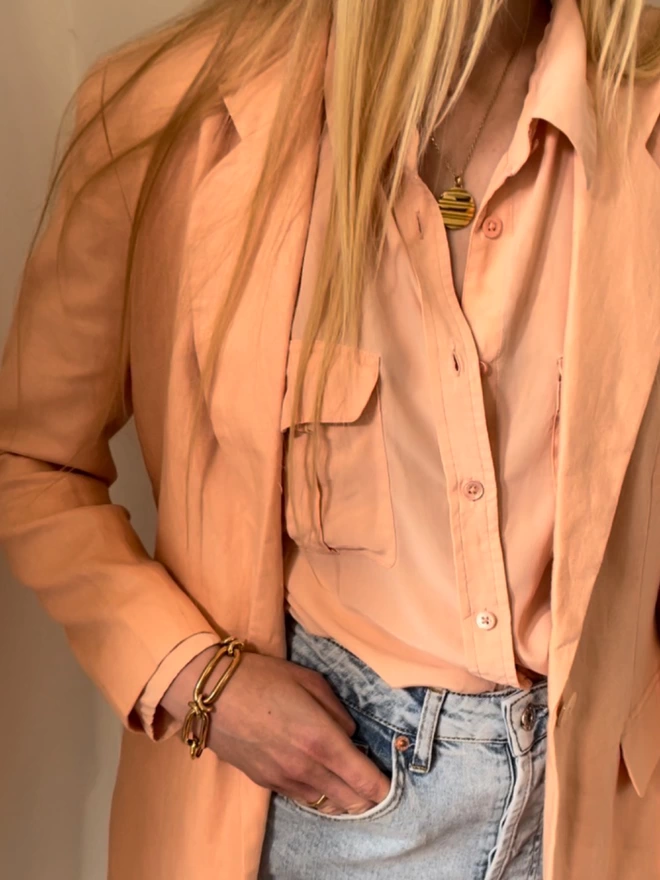 model wearing a peach silksuit jeans and a modern gold Ruddock necklace