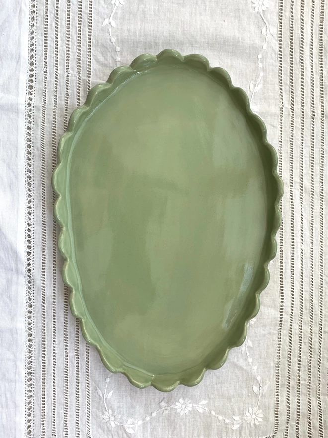 top view of oval shape sage green plae with scalloped stand up edges 