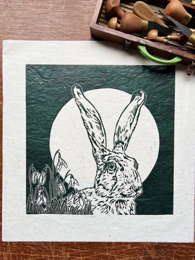 linocut of hare head with full moon and snowdrops in green ink