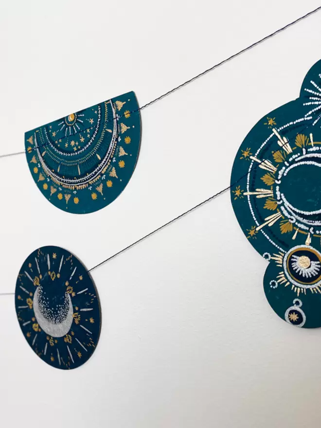 Blue and gold celestial shapes strung on white wall