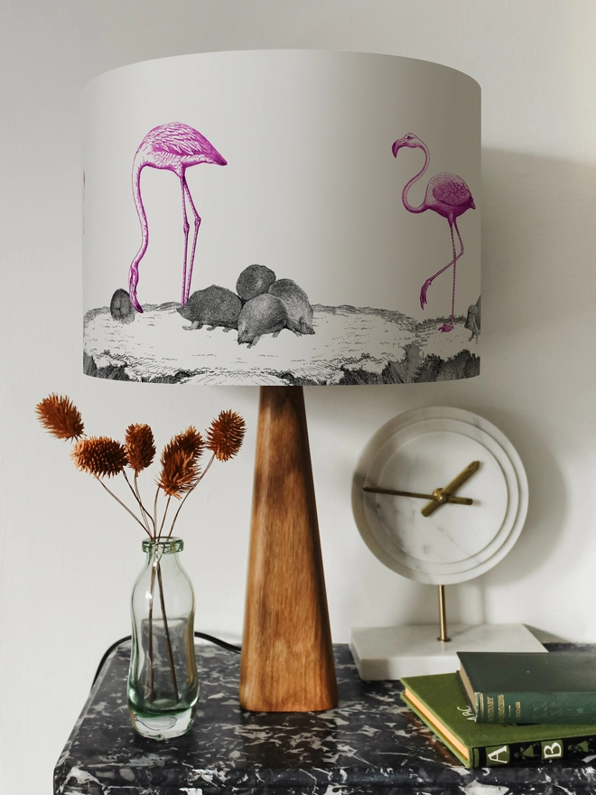 Drum Lampshade featuring pink flamingos and hedgehogs on a wooden base on a shelf with books and ornaments