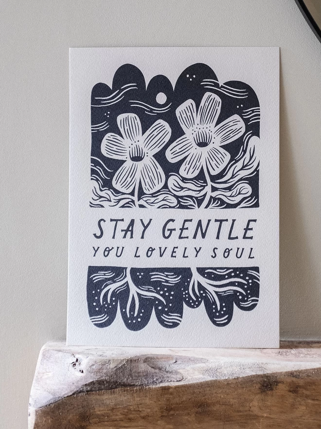 An art print containing the phrase 'Stay Gentle' with black and white flowers and lino cut style botanicals