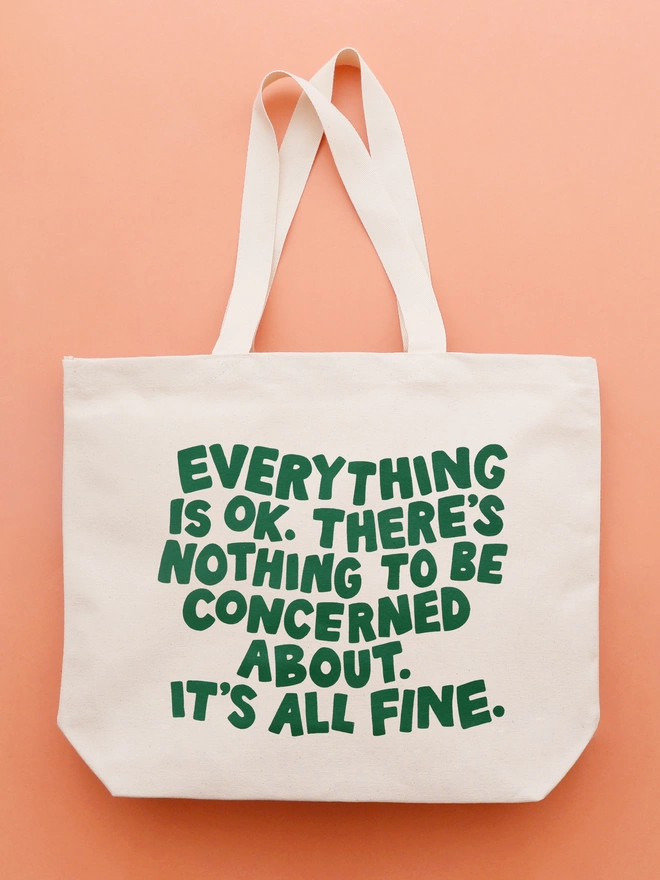 a large natural canvas tote bag bearing the words Everything is OK. There's nothing to be concerned about. It's all fine on an orange backdrop