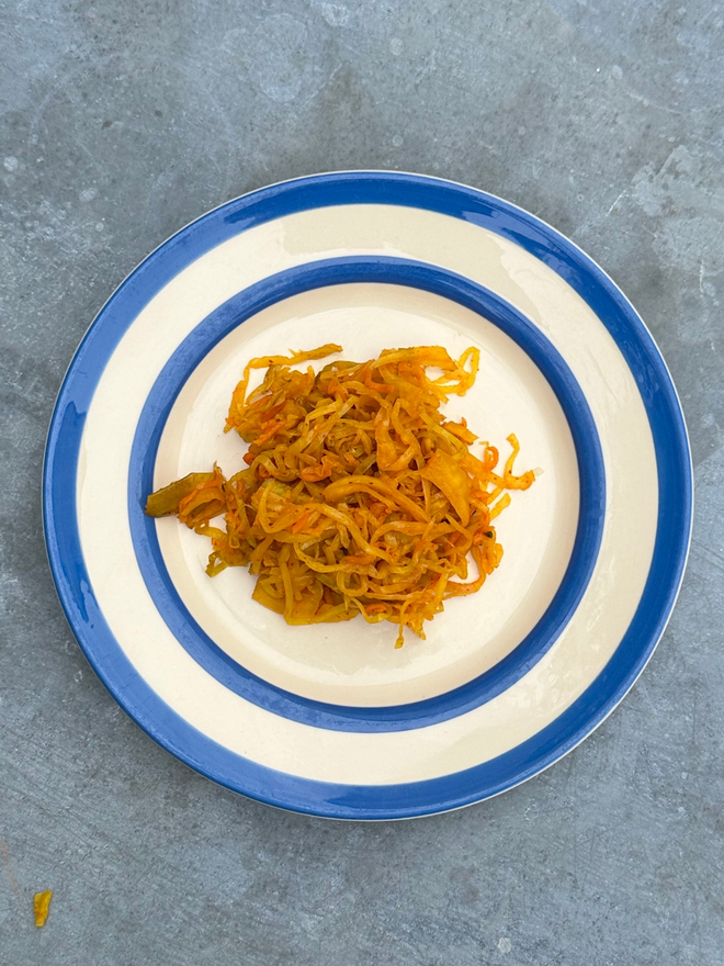 Muti Spiced Kraut On A Blue And White Plate Atop A Steel Topped Table.