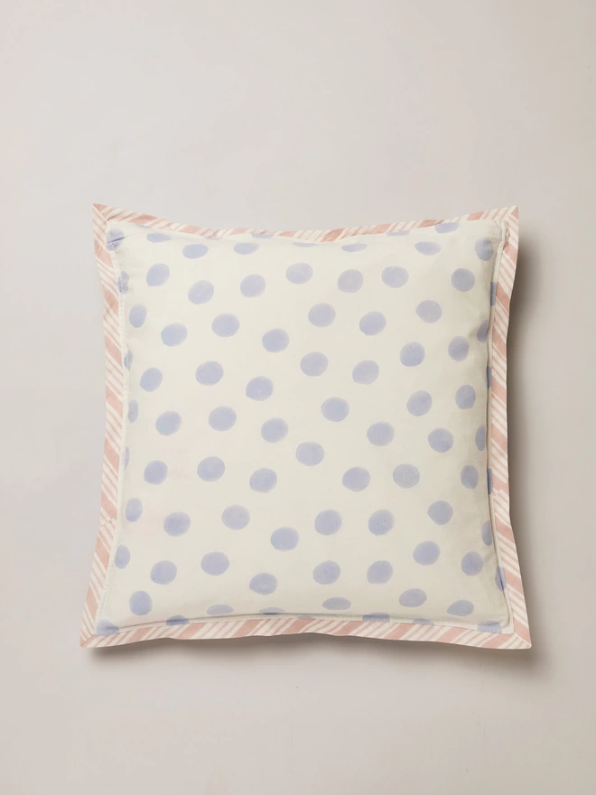 Back of block printed cushion featuring a soft blue spot on a cream ground with pink and cream striped binding 