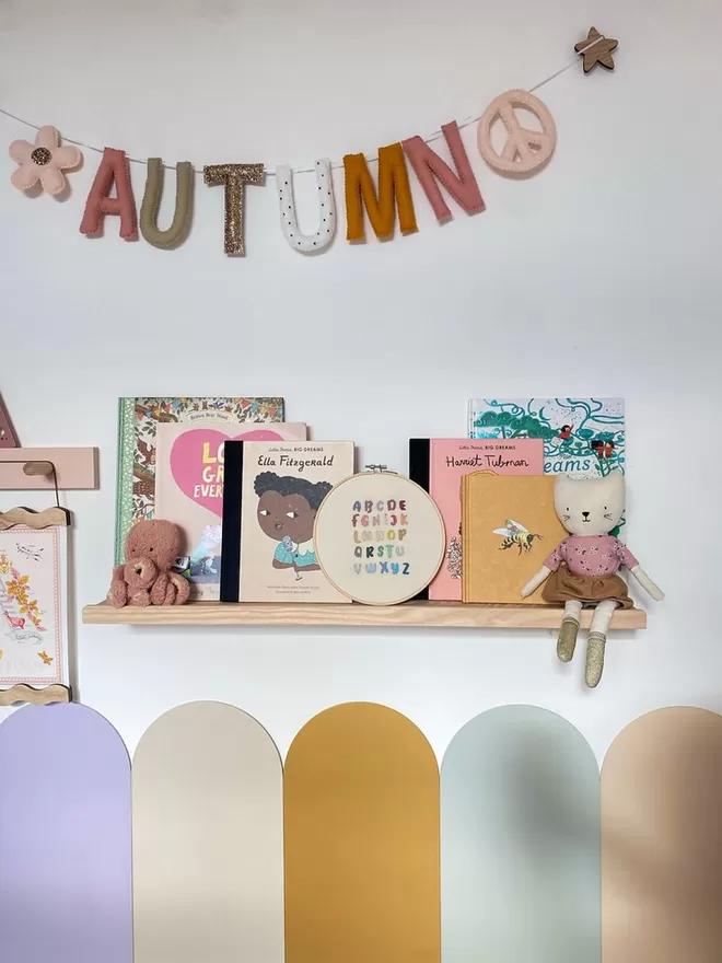 A gorgeous colourful kids room. A solid wood picture ledge shelf is styled up with kids books, teddies and children's decor.