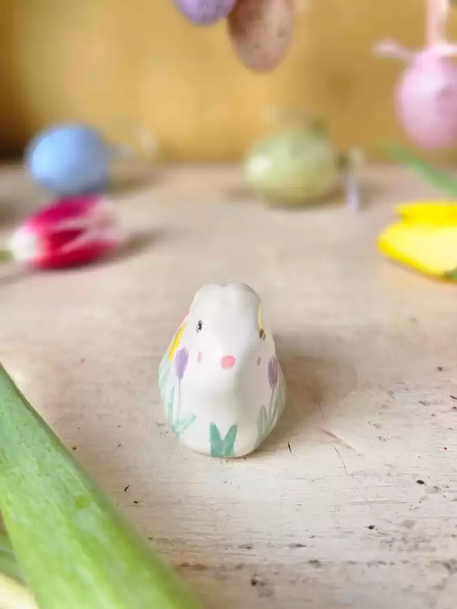 little ceramic bunny with handpainted spring flowers around the body of the rabbit.