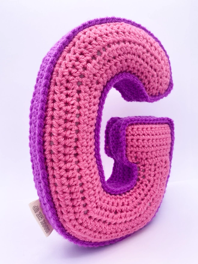 Crochet cushion shaped like the letter G in Pink and Magenta