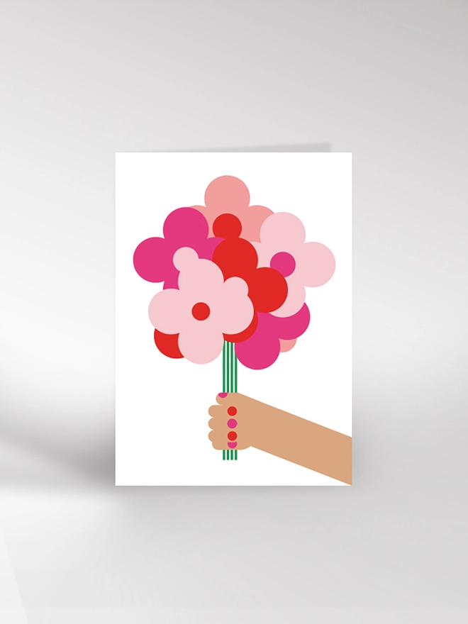 Greetings card with a hand holding a bunch of flowers