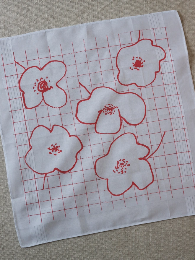 A Mr.PS Bloom Hankie printed in coral laid on a linen tablecloth