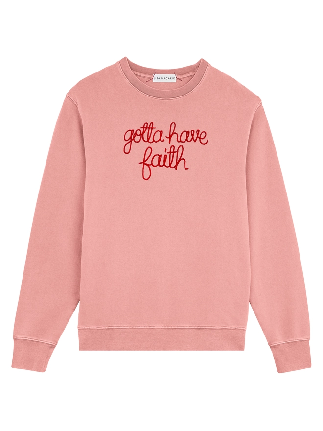 A pink sweatshirt embroidered with the lyrics gotta have faith