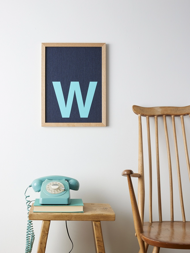 Framed turquoise initial on denim fabric