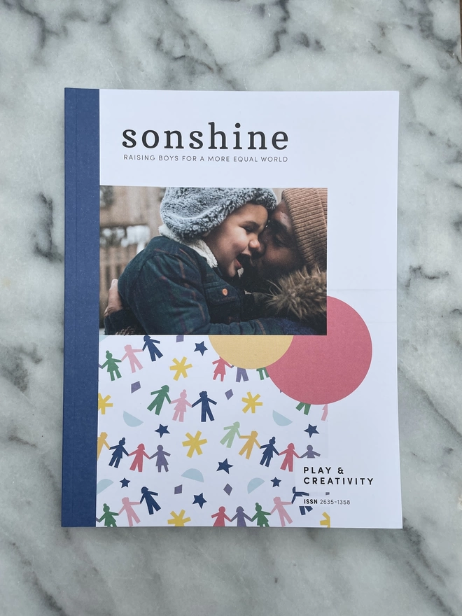 Sonshine Magazine Issue 14: Play and creativity a paper magazine featuring a photograph of a father cuddling his child both wearing warm wooly hats  