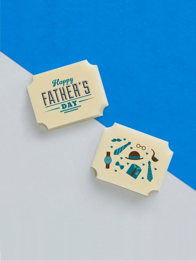 Two white chocolates for Father's Day on a blue and grey background