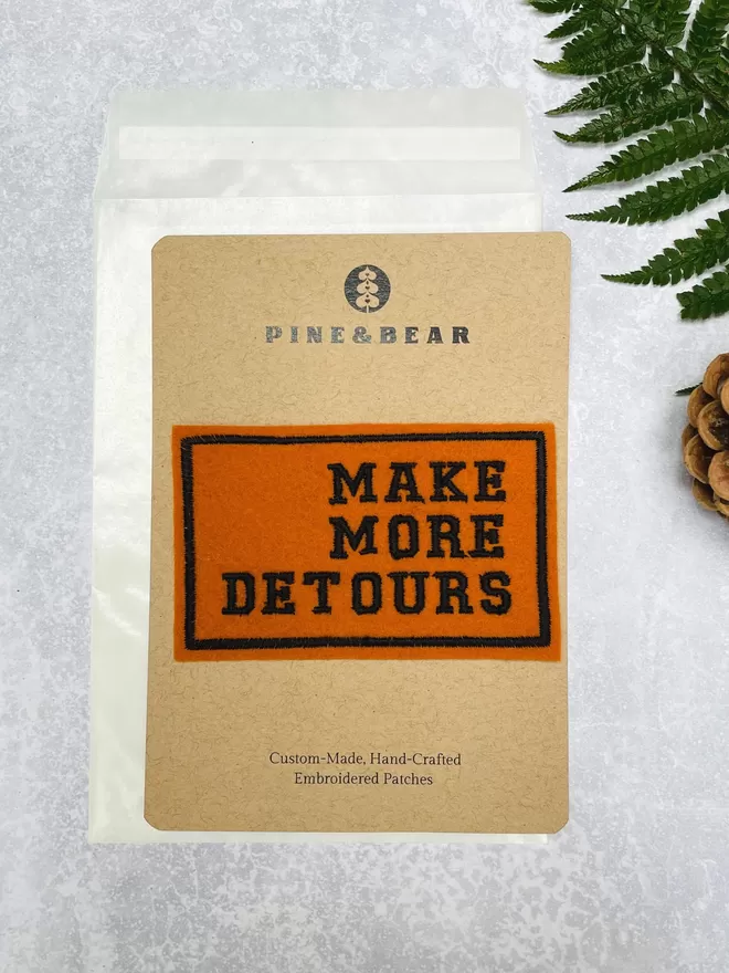 Make more detours embroidered patch on a presentation card.