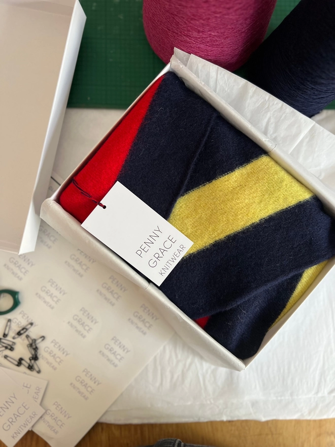 Navy scarf with colourful stripes shown in gift box