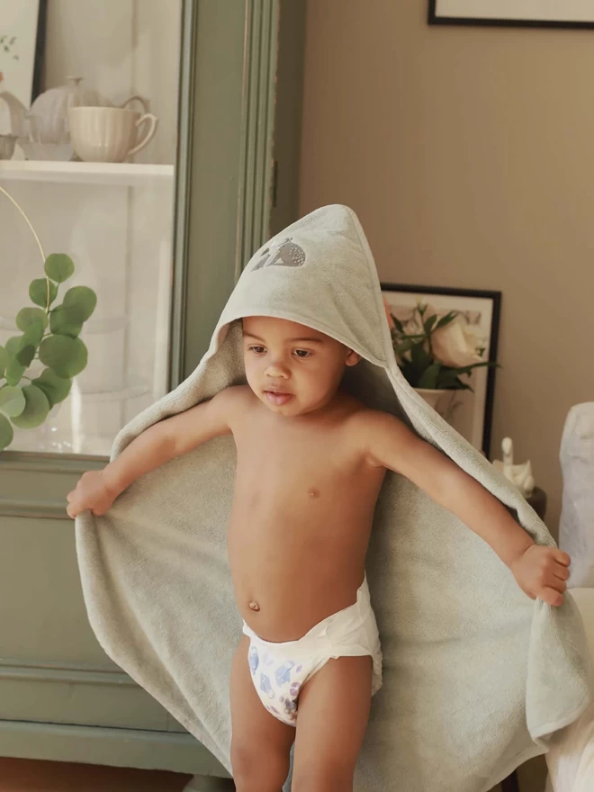 A baby on diapers wearing a hooded towel 