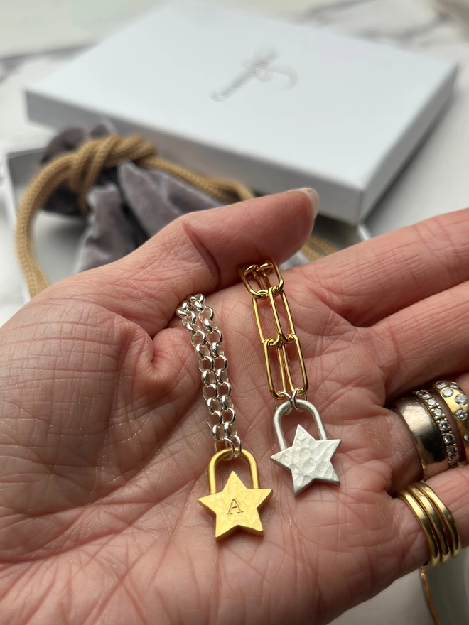 sterling silver chain with a gold star padlock charm, layered with a gold shooting star necklace on silver chain with a silver star padlock charm on a gold mini paperclip chain