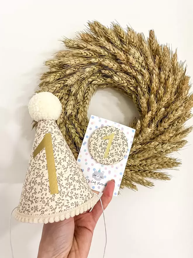 Oat Floral 1st Birthday Hat in front of a Dried Wheat Wreath