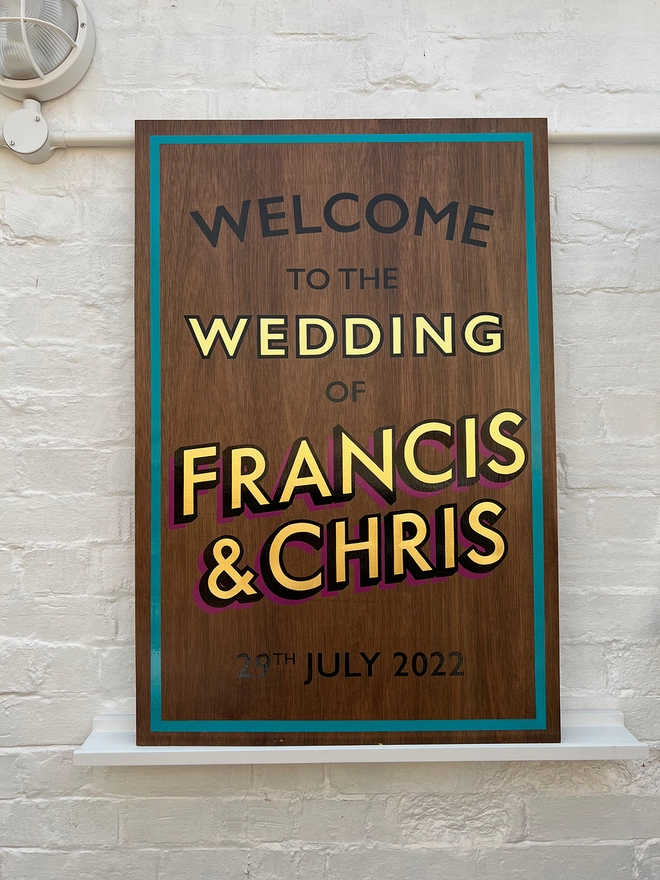 Hand painted welcome wedding sign with teal border and magenta drop shadow