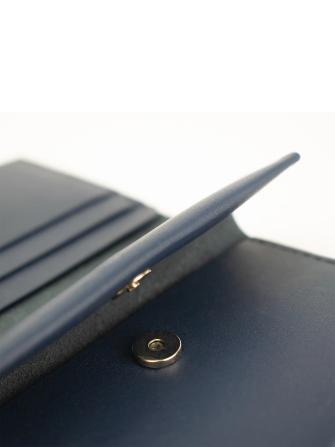 closeup of navy blue coin wallet showing the magnetic button closure. The pouch is open.