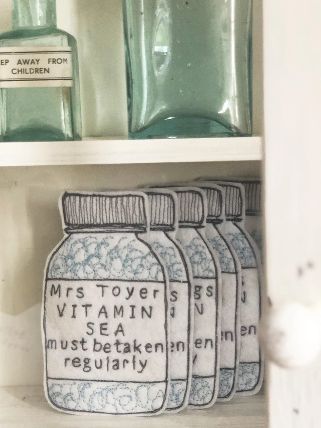 Vitamin Sea Personalised Medicine Bottles in a cabinet with glass bottles
