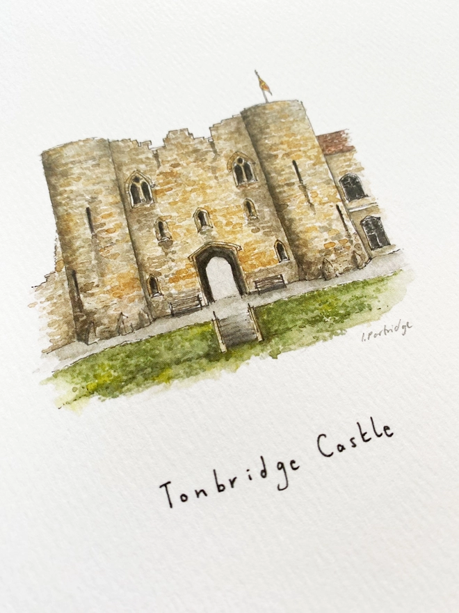Beautiful watercolour illustration of Tonbridge Castle, Tonbridge, Kent.  A wonderful sandstone coloured castle with two turrets either side of an arched entrance. A flag sits at the top and to the left a slightly eroding wall. The green castle lawn and steps down to the grass sit in front of the arch. The watercolour style is painted with a black pen outline and organic loose style with small details. A photo taken at an angle showing some of the detail. 