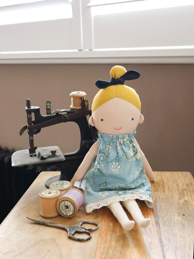 Cotton and linen doll with fair skin and blonde hair, wearing vintage inspired flower print in blue.