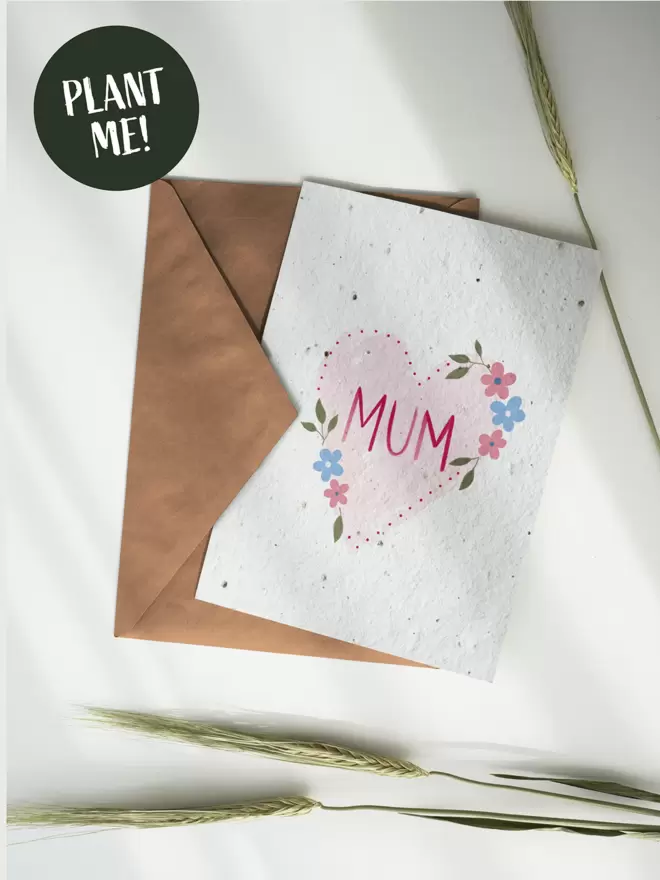 Seeded Paper Greeting Card with a heart and flowers with 'MUM' in the centre on a white background with wheat  around the card.
