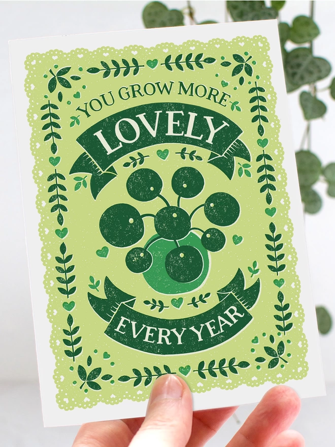 hand holding a green chinese money plant birthday card